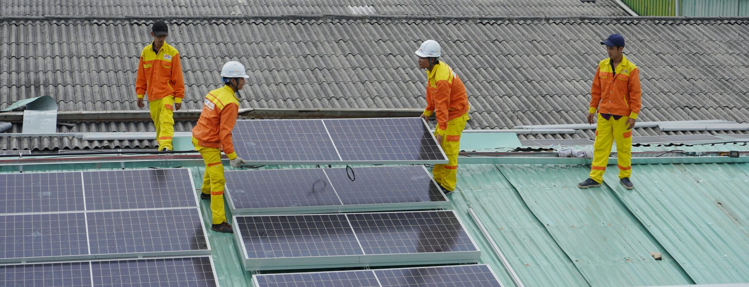 Workers installing solar panels on a roof for sustainable energy solutions.